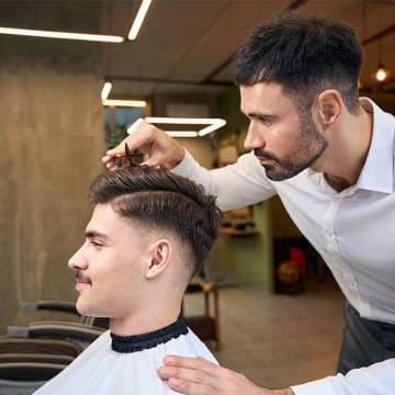 Barbeiro finalizando o corte de cabelo de um cliente